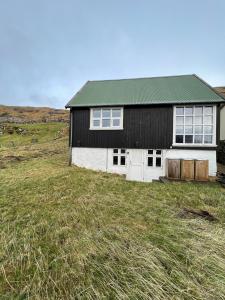 a black and white house on a grassy field at Indulge In Romance & Relaxation At Gillastova in Froðba