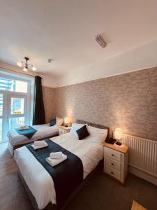 two beds in a hotel room with two lamps at The Central Hotel in Llandudno
