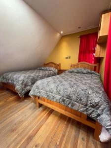 a bedroom with two beds and a red curtain at Hostal Corvatsch Chile in San Pedro de Atacama
