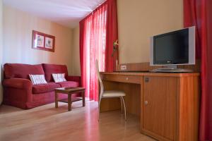 a living room with a desk with a tv and a couch at Ateneo Puerta del Sol in Madrid