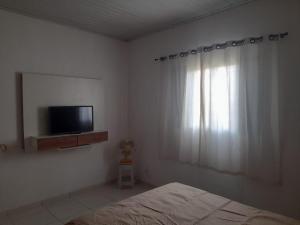 une chambre avec un lit, une télévision et une fenêtre dans l'établissement Chácara Sagrada Família, à Cachoeira Paulista