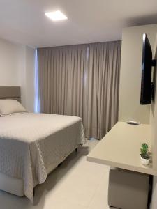 a bedroom with a bed and a desk and a television at Flat João Pessoa na praia do Bessa in João Pessoa +17 photos