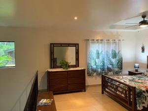 a bedroom with a bed and a dresser and a mirror at Toucan Valley Resort at Osa Mountain Village in Agua Buena
