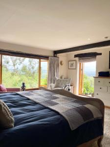 ein Schlafzimmer mit einem großen Bett mit einem großen Fenster in der Unterkunft Stunning house, fenced garden, and outdoor dining! in Hennock