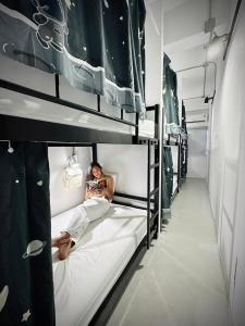 トンサラにあるPrachan Hostelの二段ベッドに座って写真を撮る女性