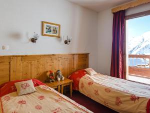 two beds in a room with a window at Ski Getaway with Shared Pool in La Toussuire