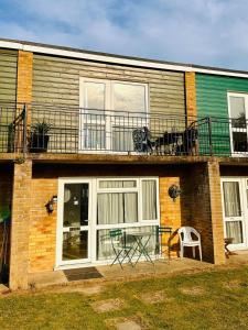 a house with a balcony with a table and chairs at Superb Chalet, Sleeps 8, Nearby Hemsby Beach In Norfolk Ref 18193B in Hemsby