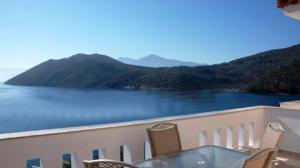a table and chairs on a balcony with a view of a lake at Villa Platanaki in Kerveli