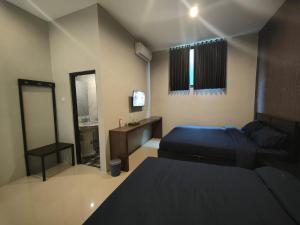 a bedroom with two beds and a television in it at BnB Home in Blimbing