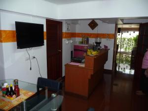 a living room with a television and a kitchen with a counter at Room For You in Bangkok