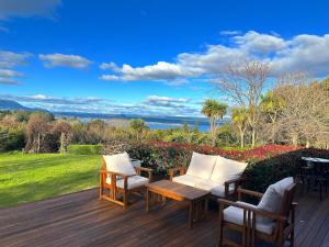 a wooden deck with two chairs and a table at Acacia Bay Lodge- Private Manor with Lake and Garden views in Taupo