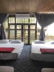 2 Betten in einem Zimmer mit Fenstern in der Unterkunft homestay nhà sàn in Buôn Alê (1)