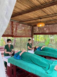 a group of people sitting on beds in a room at Khu Nghỉ dưỡng Sinh thái Nhà Lụa Retreat in Ấp Quảng Giáo