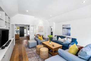 Una sala de estar con sofás azules y una mesa. en Kaleido Nook Enchanting 3BR Magic on Rugby Street, en Christchurch