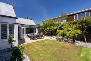 un patio con patio y una casa en Kaleido Nook Enchanting 3BR Magic on Rugby Street, en Christchurch