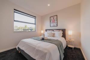 um quarto com uma cama grande e uma janela em Zenith Escapes Your Quintessential 4BR Haven em Christchurch