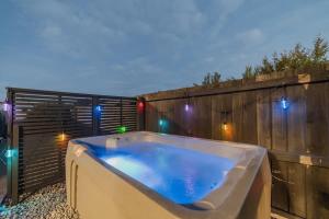 uma banheira de hidromassagem em um quintal com luzes em uma cerca em Zenith Escapes Your Quintessential 4BR Haven em Christchurch