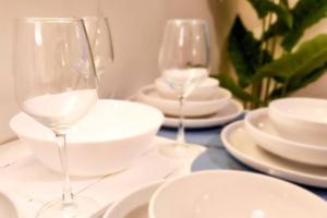 two wine glasses sitting on a table with white plates at Boho Beach Vibes 2br Apt 2 in Makati in Manila