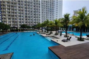 a large swimming pool with palm trees and a large building at Boho Beach Vibes 2br Apt 2 in Makati in Manila