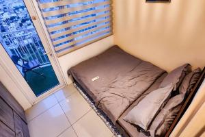a small bed in a small room with a window at Boho Beach Vibes 2br Apt 2 in Makati in Manila