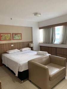 a bedroom with a large bed and a chair at Flat Particular Marizienne Hotel Saint Moritz 31 in Torto