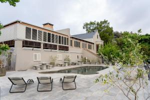 an exterior view of a house with a pool and chairs at Avemore Orchard Apartment - with full Backup power in Stellenbosch