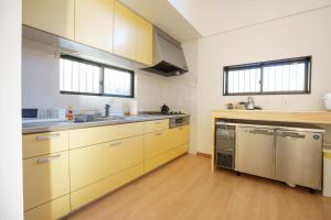 a kitchen with yellow cabinets and stainless steel appliances at VILLA ATAMI -Nagomi- in Atami