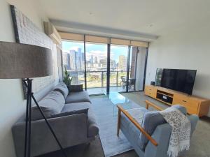 a living room with a couch and a television at Harbour Escape Apartments Docklands in Melbourne