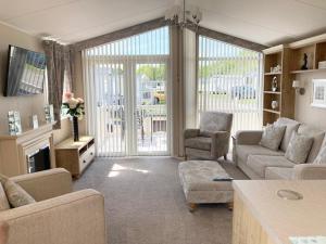 a living room with a couch and chairs and a tv at Vogue at Primrose in Reighton