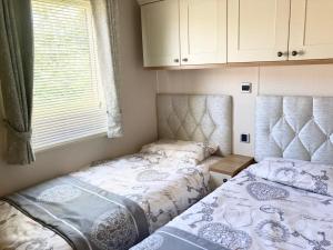 two twin beds in a room with a window at Vogue at Primrose in Reighton