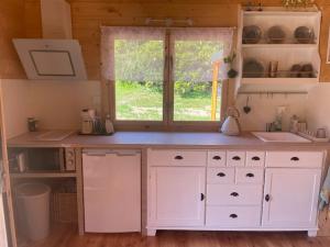 a kitchen with white cabinets and a window at Charmant chalet de campagne in Grandrupt