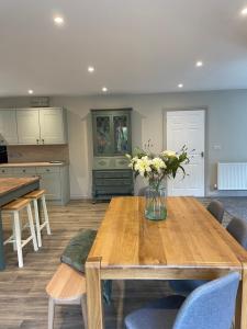 a kitchen with a wooden table with a vase of flowers on it at Llety Cynnes in Machynlleth