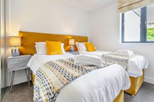 two beds in a bedroom with yellow pillows at 4 Rockham - Luxury Apartment at Byron Woolacombe, only 4 minute walk to Woolacombe Beach! in Woolacombe +25 photos