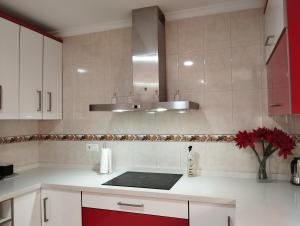 una cucina con armadi bianchi e dettagli rossi di Adosado Centro Urbano 3 Dorm Patio Terraza Wi-fi Puente Genil 1-6 Huésped a Puente Genil Altre 30 foto