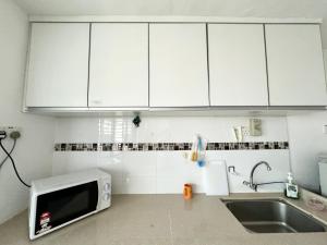 a kitchen with white cabinets and a sink and a microwave at Central Georgetown Cozy Hideaway, Penang in George Town