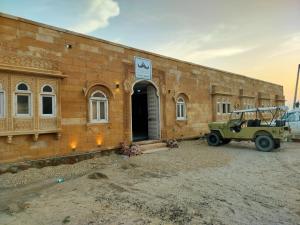 una jeep verde parcheggiata di fronte a un edificio di mattoni di Dune Delite Jaisalmer a Sām