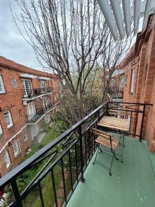 a balcony with a wooden bench and a tree at Regents Gate East Melbourne in Melbourne