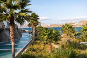 a view of the water at the resort with palm trees at Aeonic Suites and Spa in Mikonos