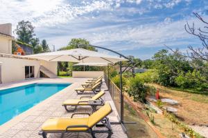 ein Pool mit gelben Liegestühlen und einem Sonnenschirm in der Unterkunft Casa da Naia in Adaúfe