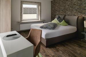 a bedroom with a bed and a desk and a window at Pension Waldhorn in Aidlingen