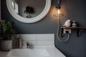 a bathroom with a sink with a mirror and a light at Sailor's Catch in Hokitika