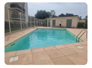 a swimming pool with blue water in front of a building at Un appartement calme et élégant in Avignon