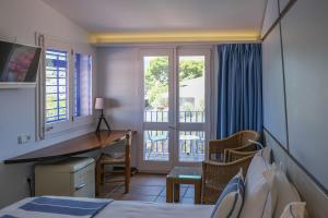 a bedroom with a bed and a desk and a balcony at Hotel Blaumar Cadaqués by Fimedhotels in Cadaqués