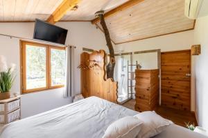 a bedroom with a large bed with a tv on the wall at Cabane Dans les Arbres, Domaine de l Ogliastru in Olmeto