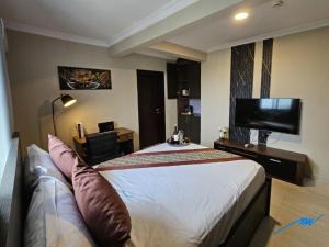 a hotel room with a bed and a flat screen tv at Mansah Plus Hotel and Apartments in Accra