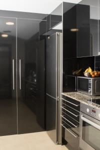 a kitchen with stainless steel appliances and black cabinets at Modern Beach Apartment - La Maca in Tamariu +21 photos
