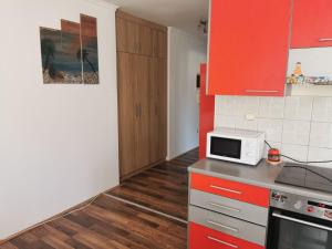 a kitchen with red cabinets and a microwave at Dunav 012 in Veliko Gradište