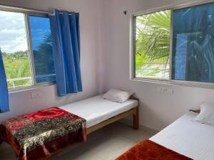 two beds in a room with two windows at Senamura Yoga Ashram Guesthouse in Bodh Gaya