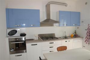 una cucina con armadi blu, lavandino e forno a microonde di Nereadi Family Apartment a Lido di Jesolo