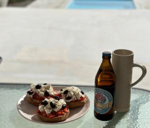 Dos sándwiches en un plato junto a una botella de cerveza. en Komos Beach Estate, en Kalamaki